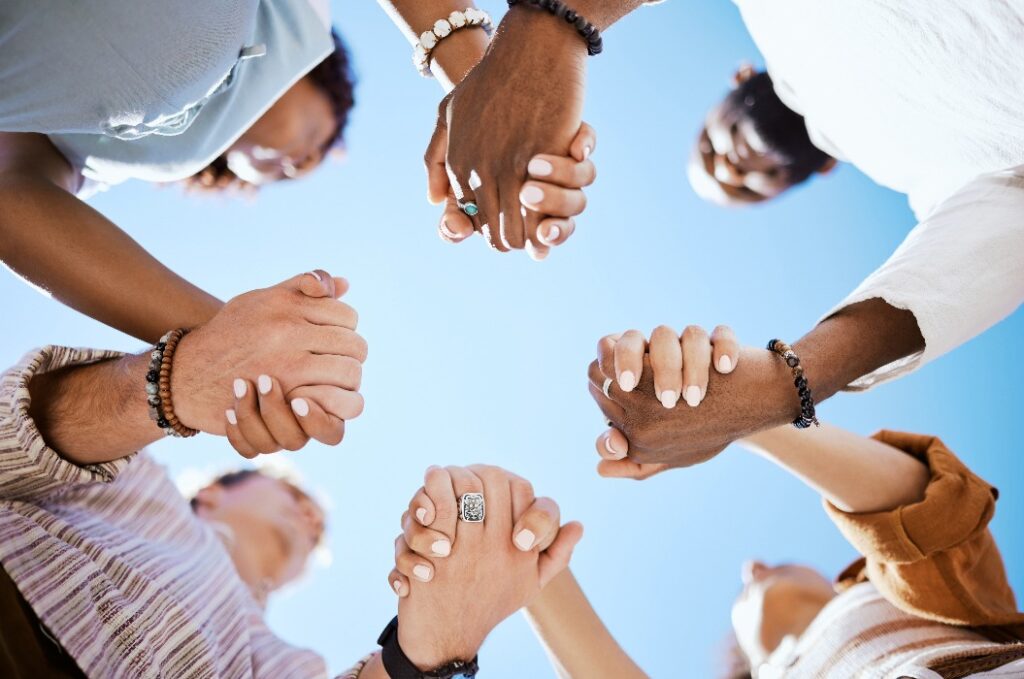 Vielfalt, Unterstützung und Menschen, die sich in Vertrauen und Einigkeit für die Gemeinschaft vor dem Hintergrund des Himmels an den Händen halten.